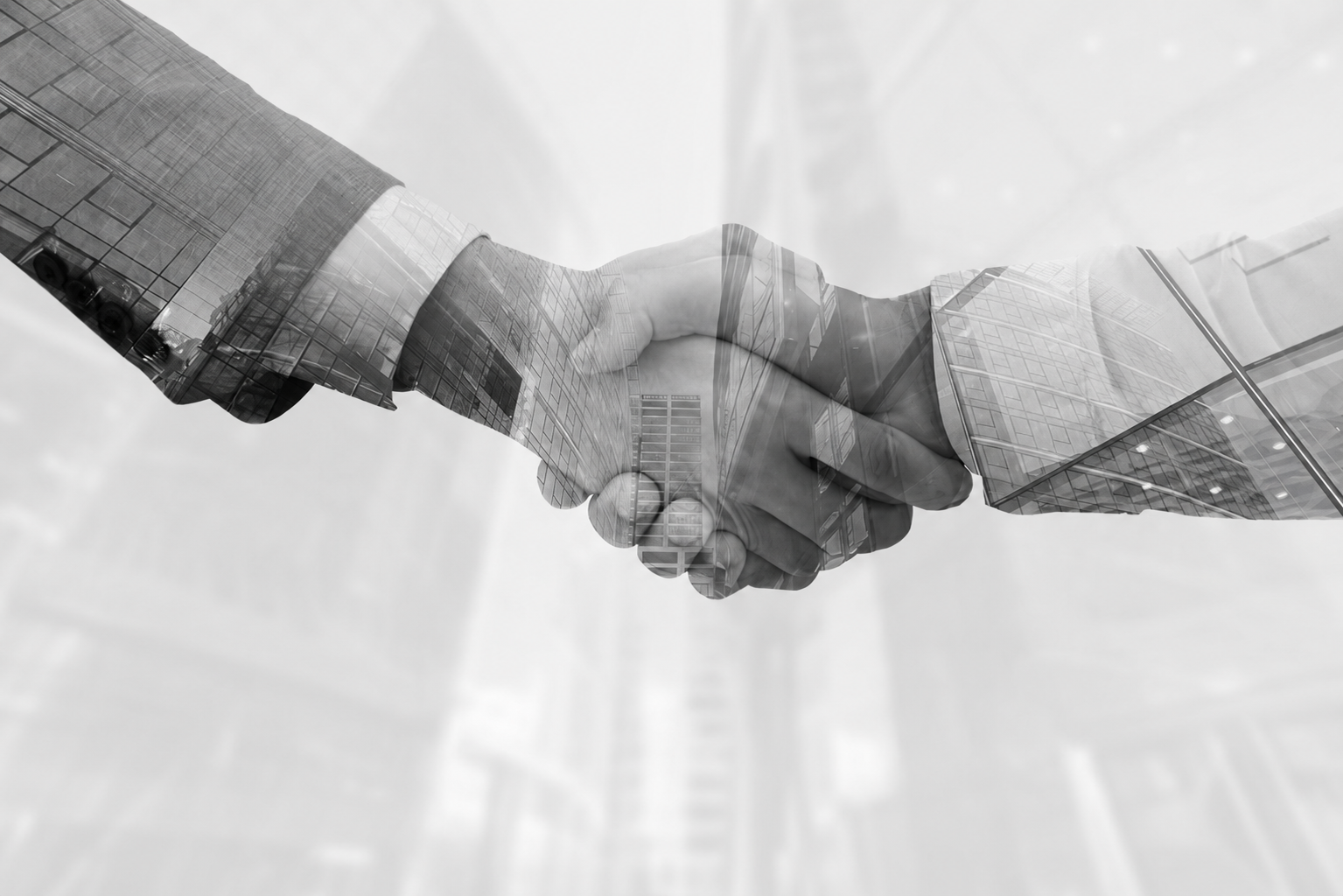 Two business professionals shaking hands in front of a modern office building, symbolizing a successful partnership.